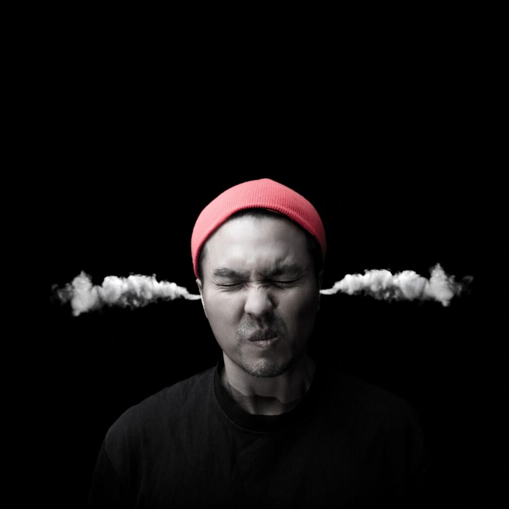 a picture of a male with a red hat, eyes closed, and smoke coming out of his ears with a black background