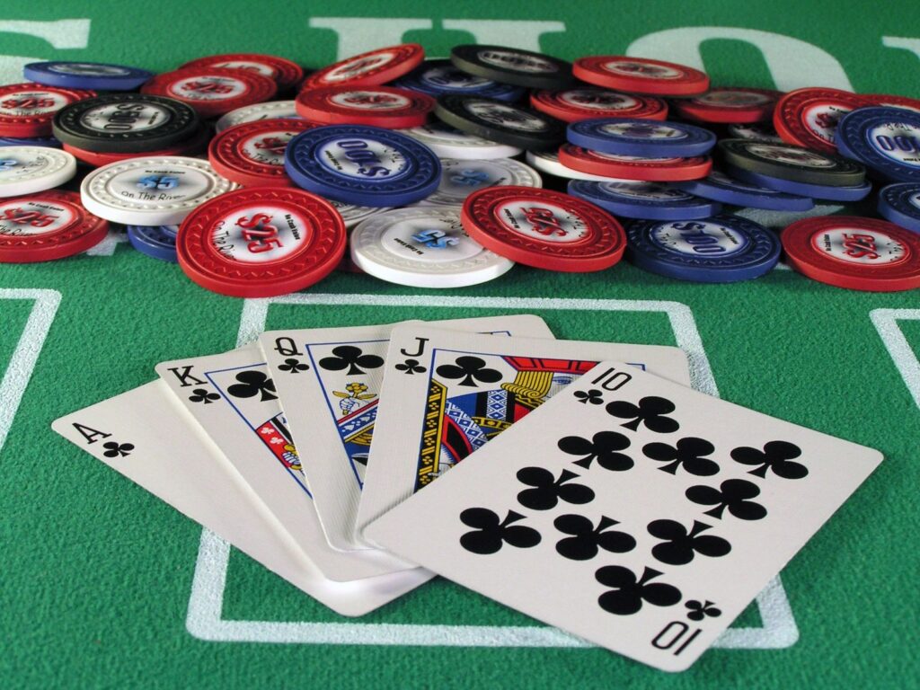 a picture of the best hand in poker, Royal Flush, suited in clovers with a pile a poker chips in front of it