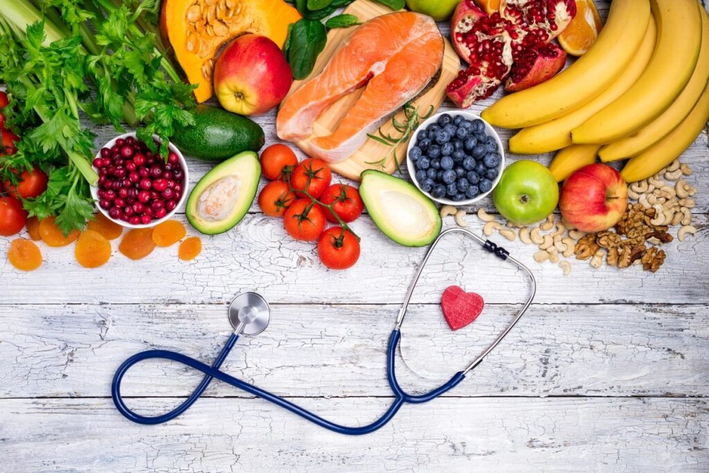 a picture of fruit and vegetables with a stethoscope laying down around a red heart