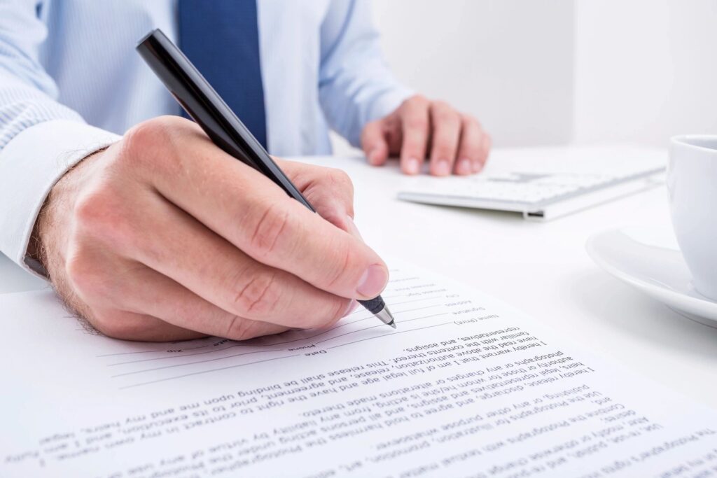 a picture showing a hand signing a contract